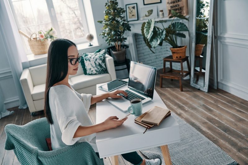 Working from home. Top view of beautiful young woman working using laptop while sitting in home office